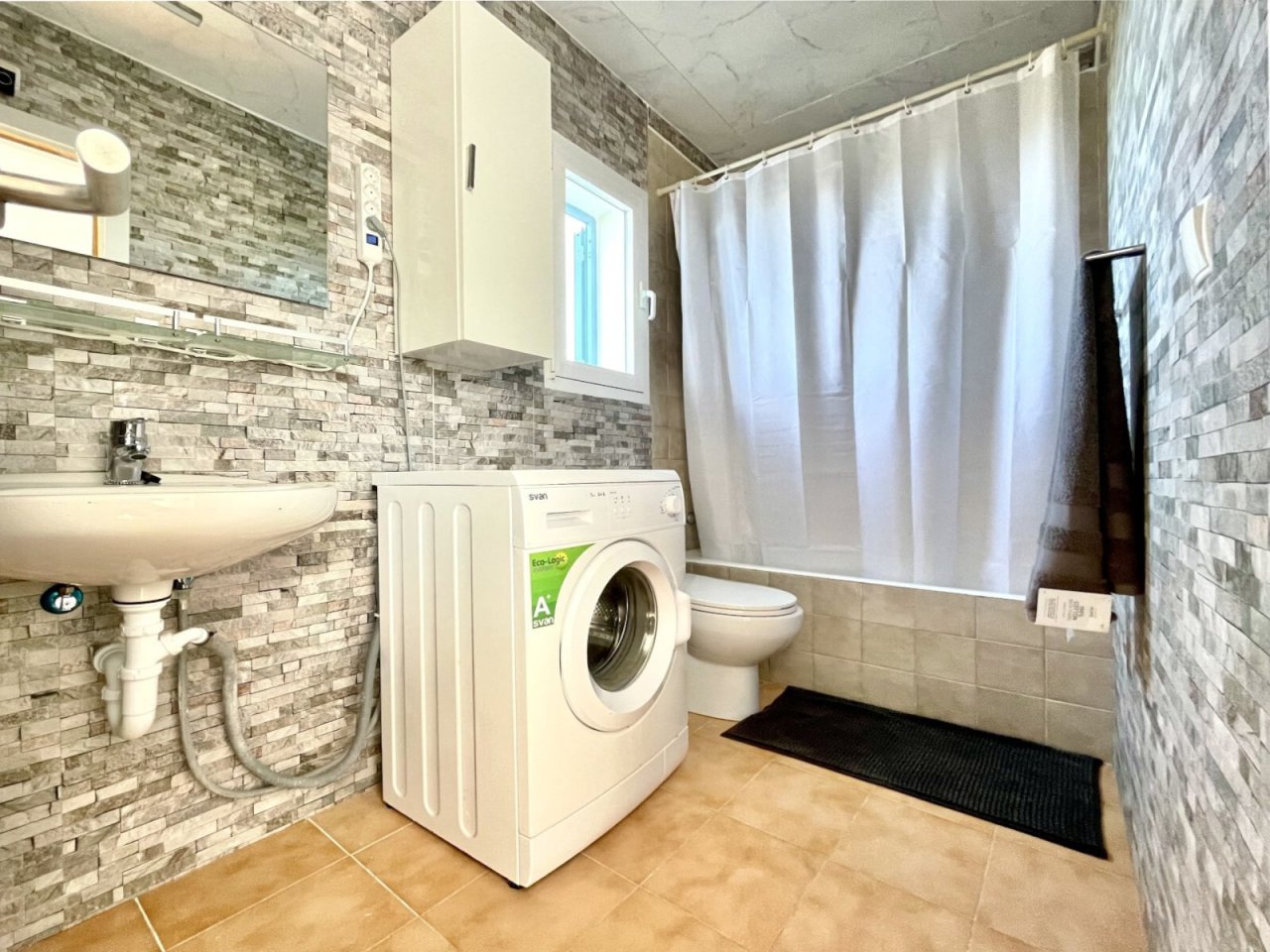 Praktisches Waschbad mit integriertem Wäschebereich und modernen Sanitärinstallationen Praktisches Waschbad mit integriertem Wäschebereich und modernen Sanitärinstallationen