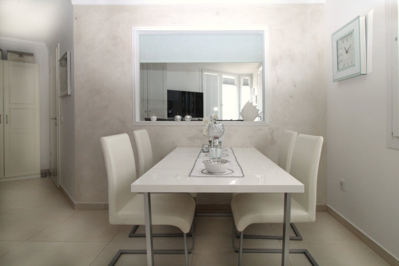 Elegantes Esszimmer mit raumhohem Spiegel und offener Sichtachse zur Wohnlandschaft