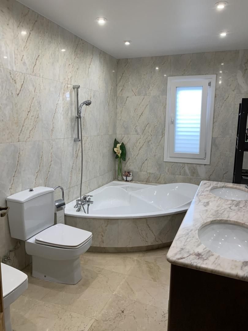 Luxuriöses Badezimmer mit Eckwanne, Marmor-Verkleidung und hochwertiger Sanitärausstattung Luxuriöses Badezimmer mit Eckwanne, Marmor-Verkleidung und hochwertiger Sanitärausstattung