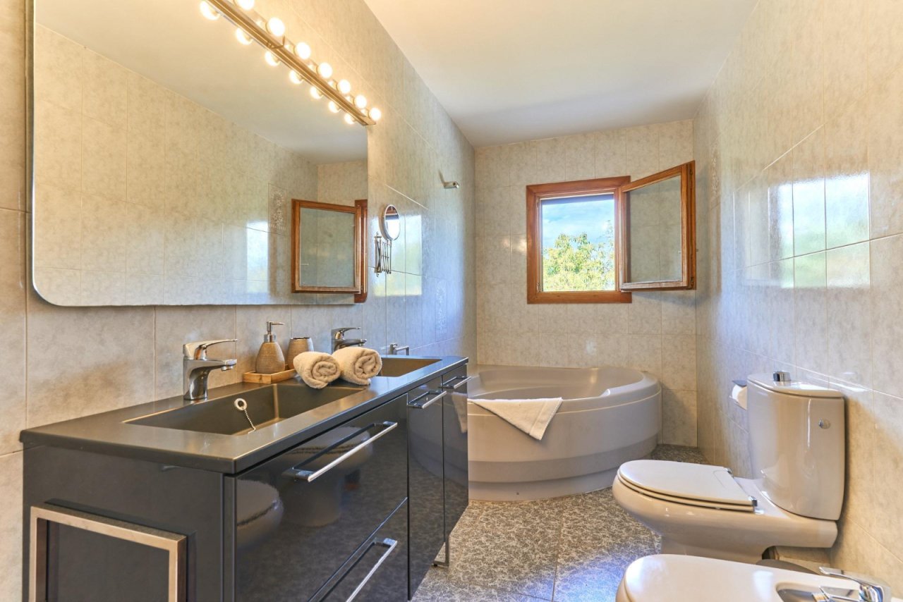 Elegantes Badezimmer mit Eckbadewanne, Doppelwaschtisch und großflächiger Fensterfront Elegantes Badezimmer mit Eckbadewanne, Doppelwaschtisch und großflächiger Fensterfront