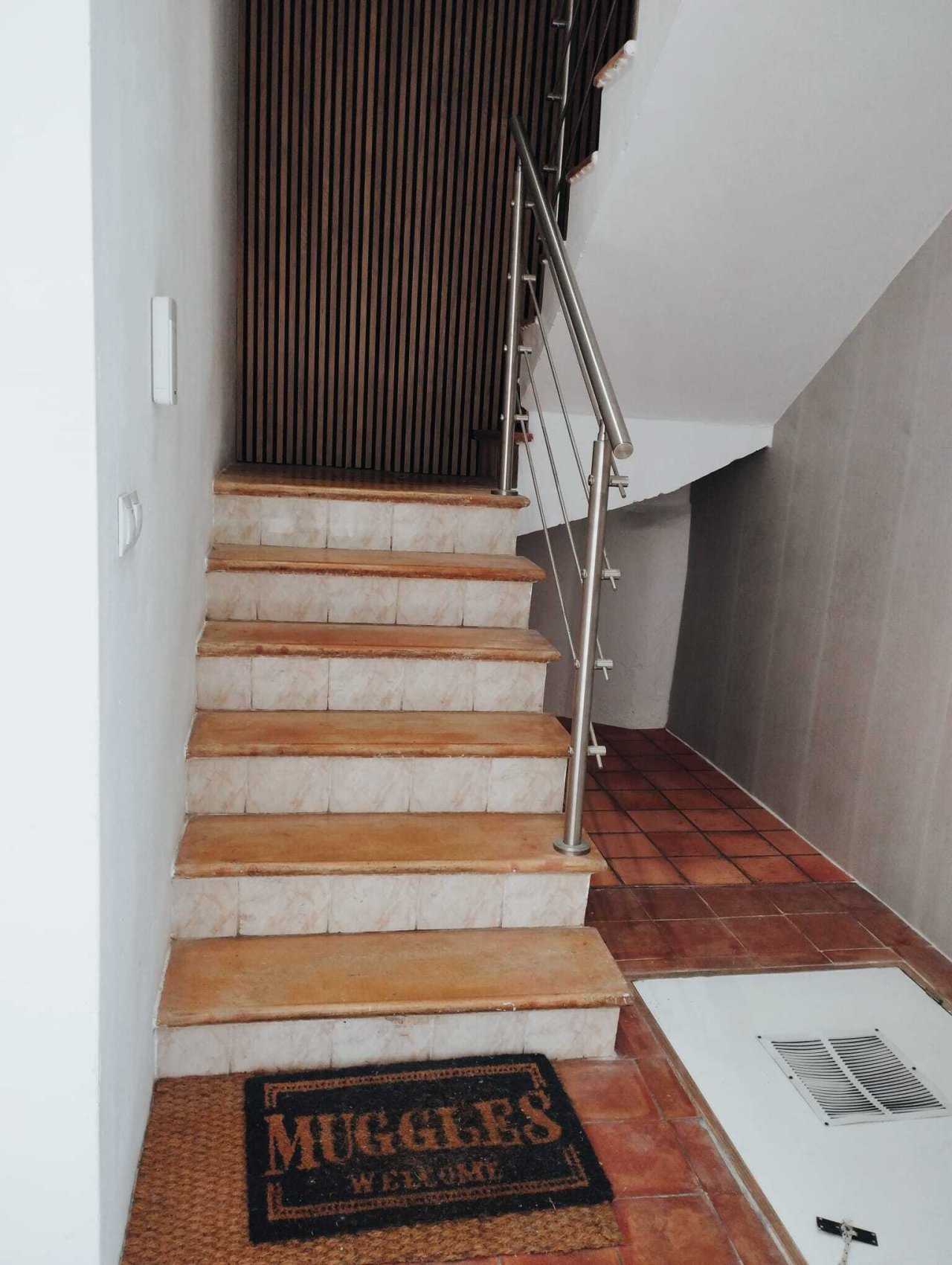 Elegante Treppe mit Natursteinstufen und modernem Edelstahl-Geländer
