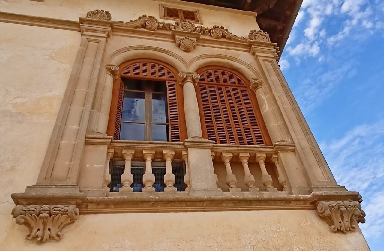 Klassizistische Fensterfront mit aufwendig ornamentierter Steinrahmung und Juliette-Balkon Klassizistische Fensterfront mit aufwendig ornamentierter Steinrahmung und Juliette-Balkon