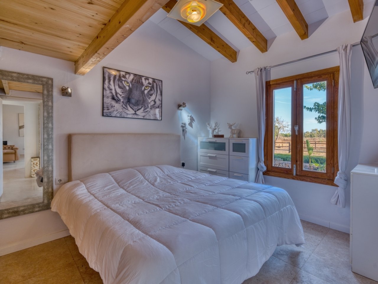 Schlafzimmer mit Holzbalkendecke und französischen Glastüren zum Landschaftsblick