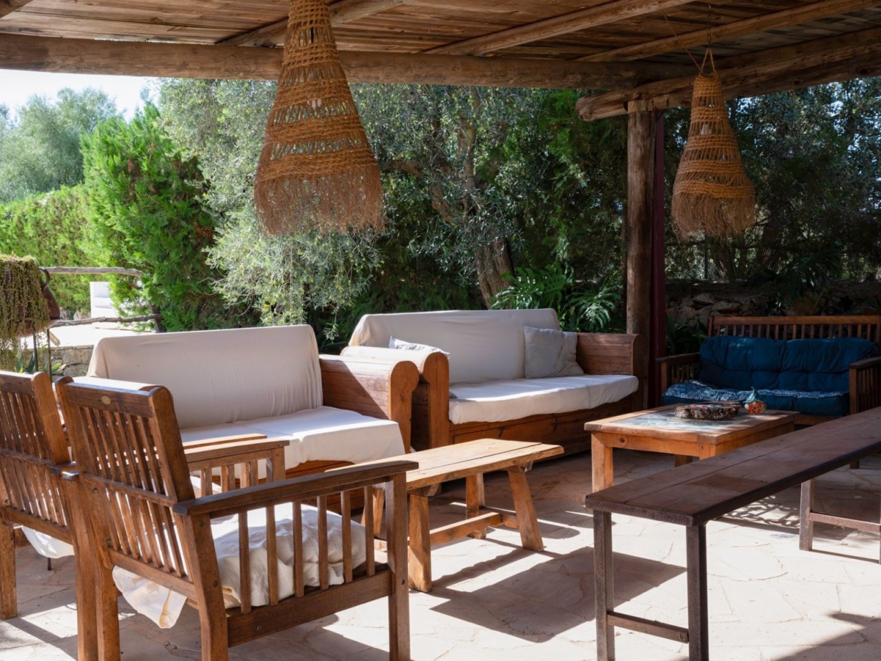 Entspannungsbereich unter Pergola: Überdachte Lounge mit massiven Holzbalken und Gartenblick Entspannungsbereich unter Pergola: Überdachte Lounge mit massiven Holzbalken und Gartenblick