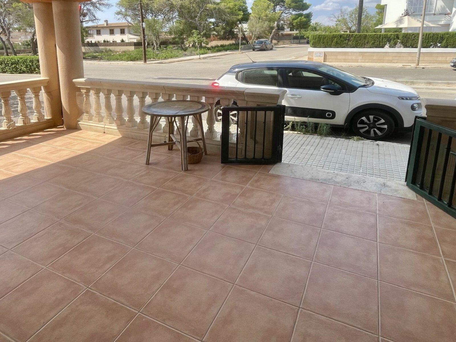 Sonnendurchflutete Terrasse mit hochwertiger Steinbelagfläche und direktem Straßenzugang