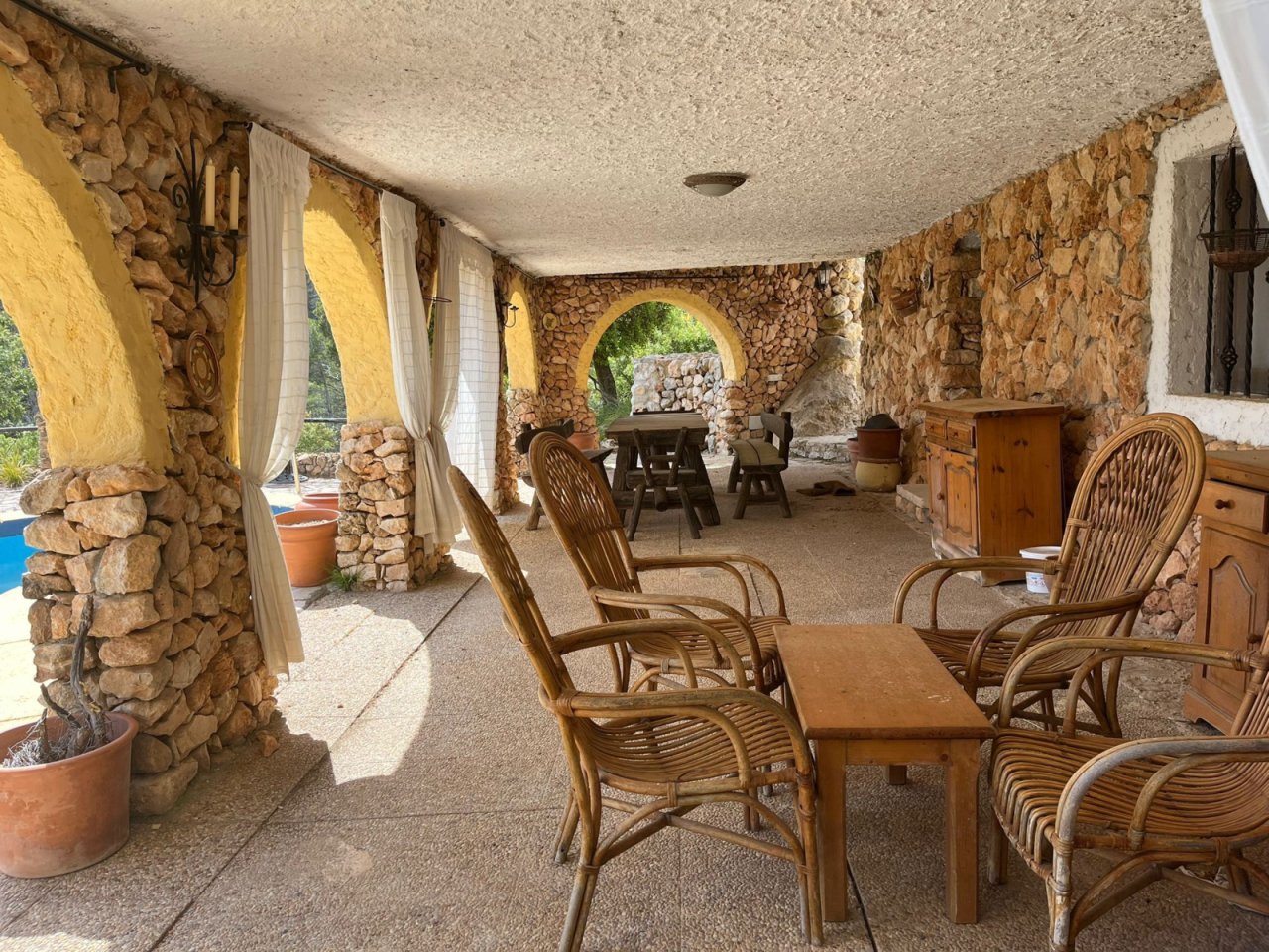 Überdachte Lounge mit Natursteinarkaden – Geräumiger Rückzugsort mit rustikalem Charme und Durchgangsbereich zur Terrasse Überdachte Lounge mit Natursteinarkaden – Geräumiger Rückzugsort mit rustikalem Charme und Durchgangsbereich zur Terrasse