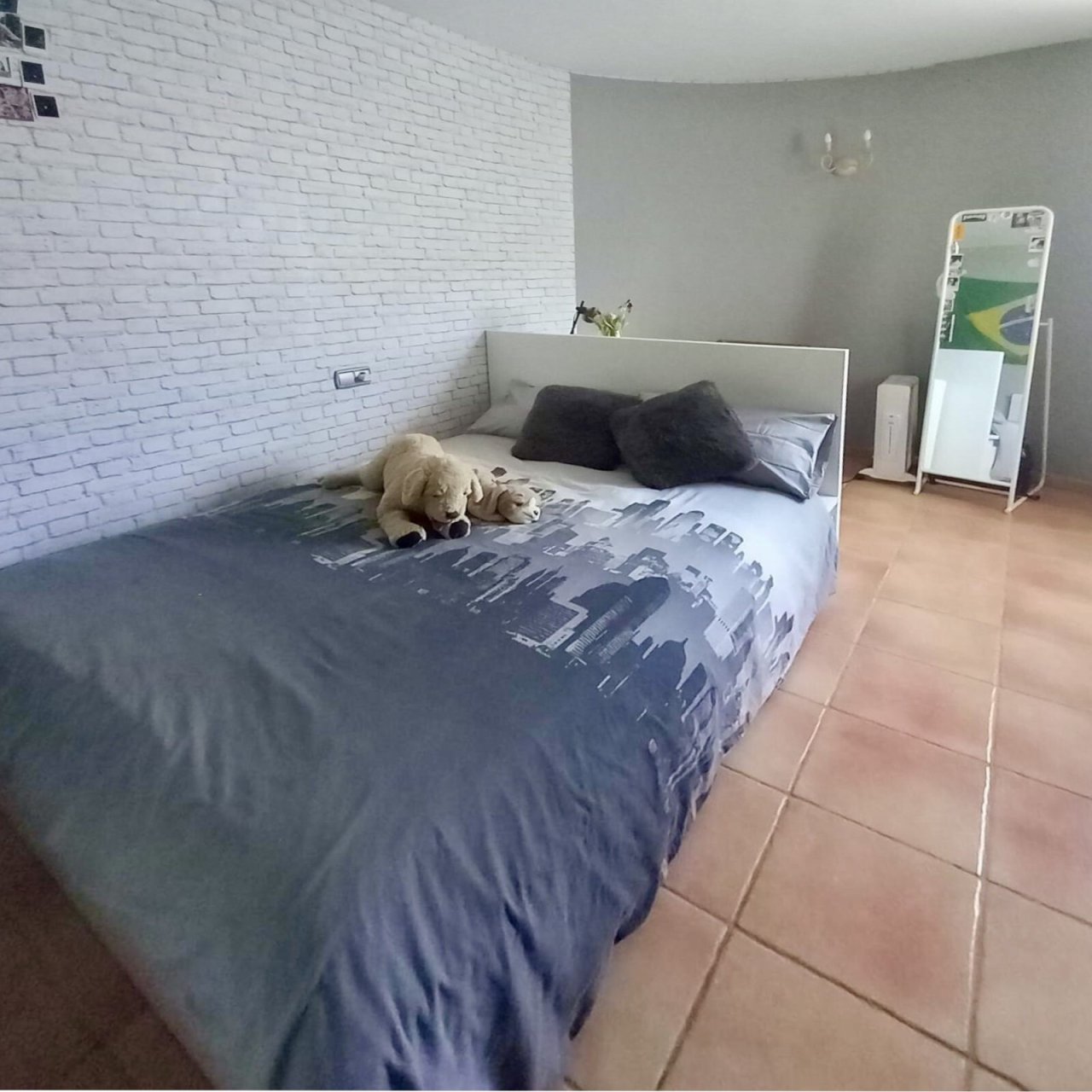 Geräumiges Schlafzimmer mit Ziegelsteinakzent und Terrakotta-Fliesenboden