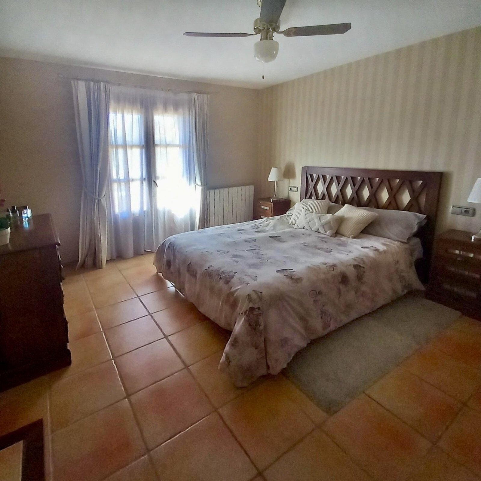 Helles Schlafzimmer mit Deckenventilator und französischen Balkontüren zum privaten Außenbereich