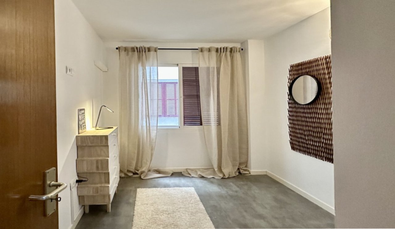 Helles Schlafzimmer mit großflächigem Fenster und direktem Balkonzugang