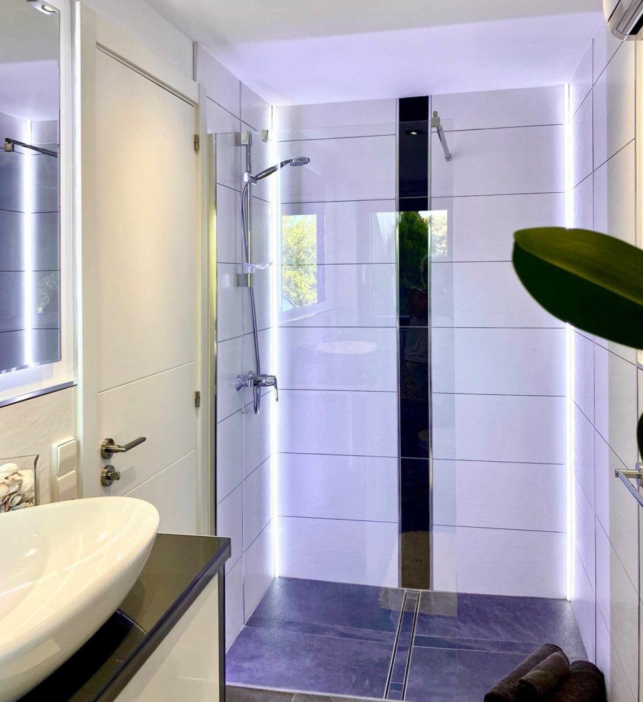 Luxuriöse Duschzone mit bodenebener Ausführung, Glasabtrennung und atmosphärischer LED-Beleuchtung Luxuriöse Duschzone mit bodenebener Ausführung, Glasabtrennung und atmosphärischer LED-Beleuchtung