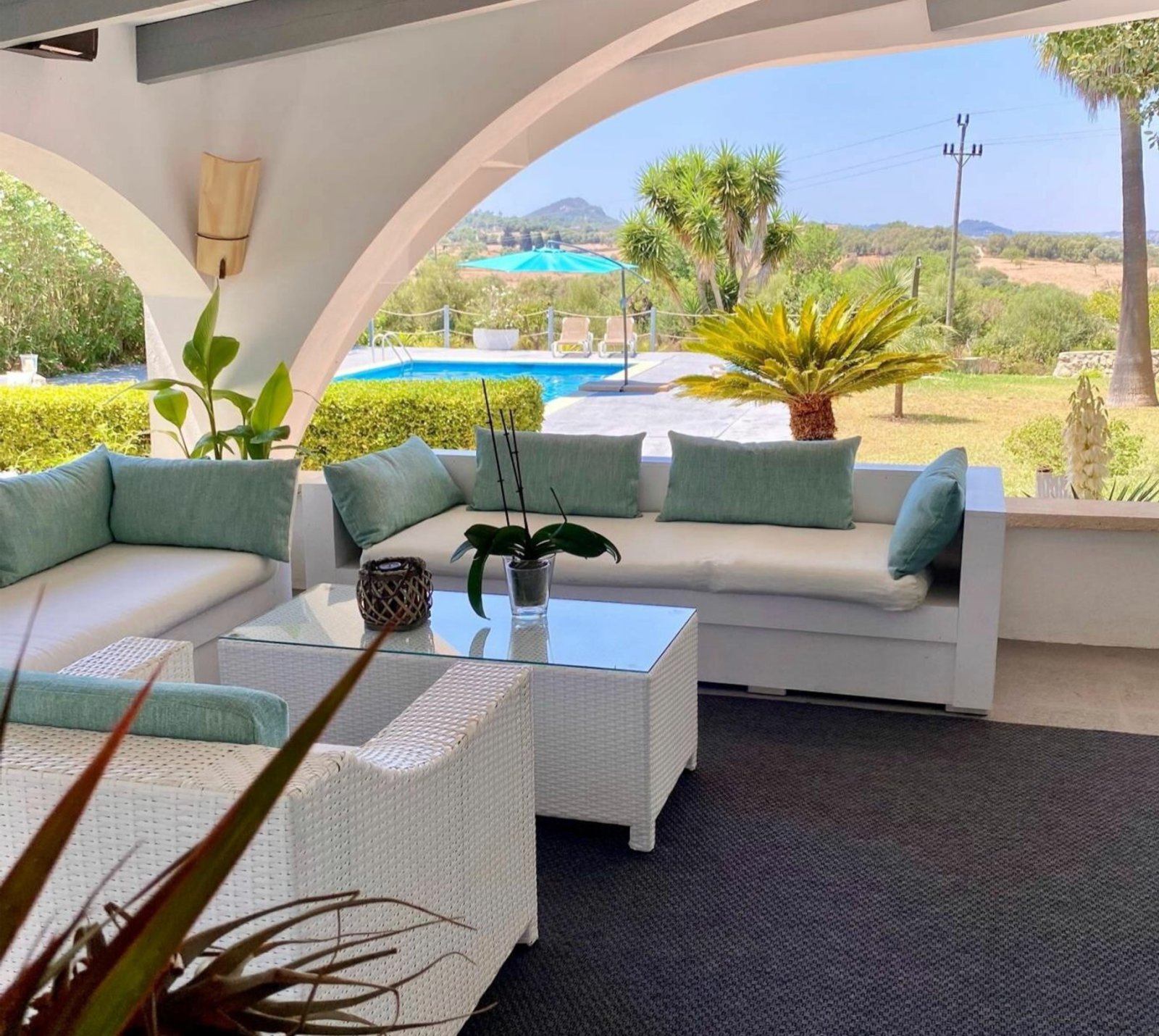 Überdachte Lounge-Terrasse mit eleganten Bogenkonstruktionen und freiem Blick auf Pool und Landschaft Überdachte Lounge-Terrasse mit eleganten Bogenkonstruktionen und freiem Blick auf Pool und Landschaft