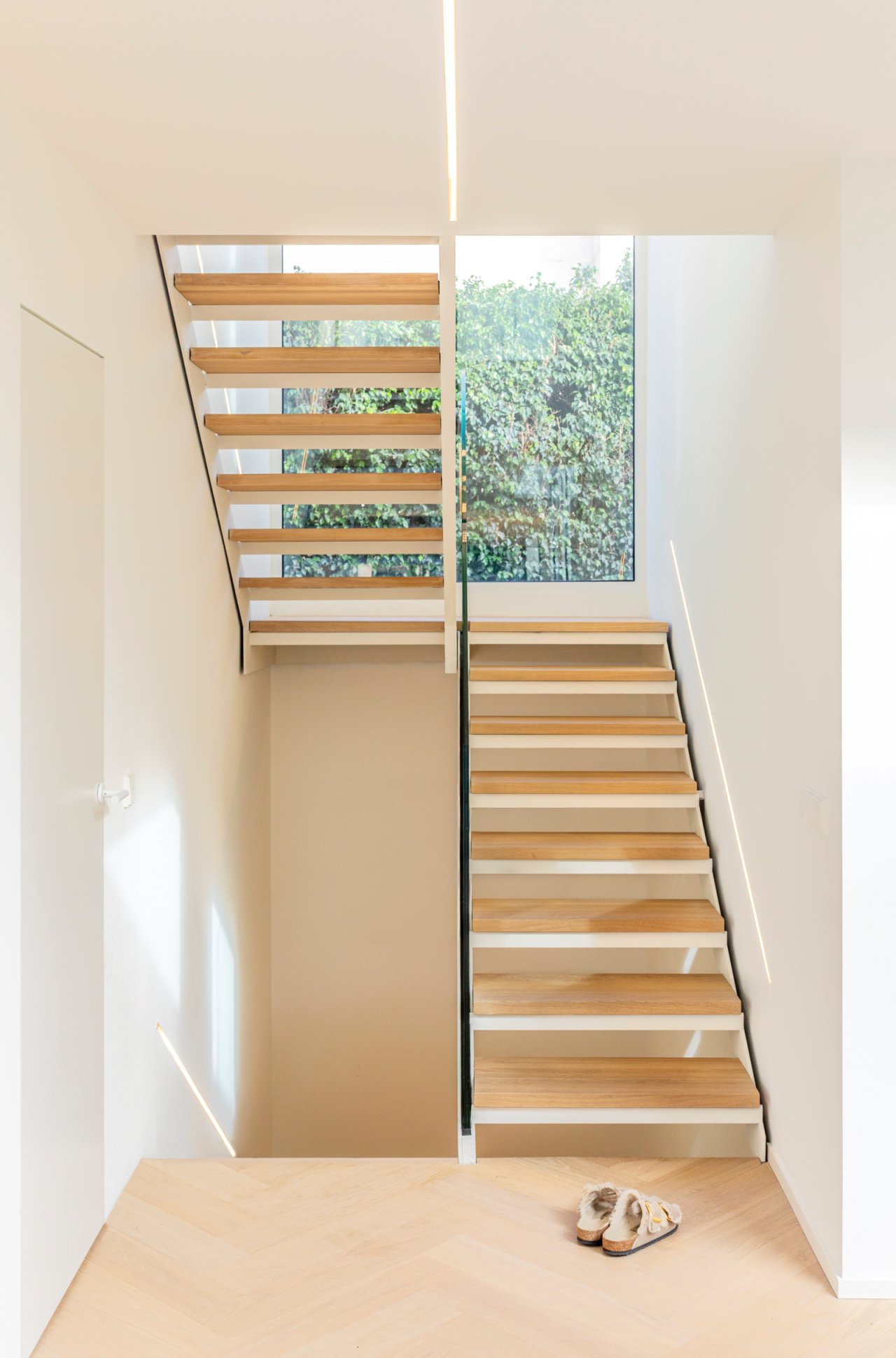 Moderne Treppe mit durchdachtem Raumkonzept und großflächiger Fensterfront zum Garten