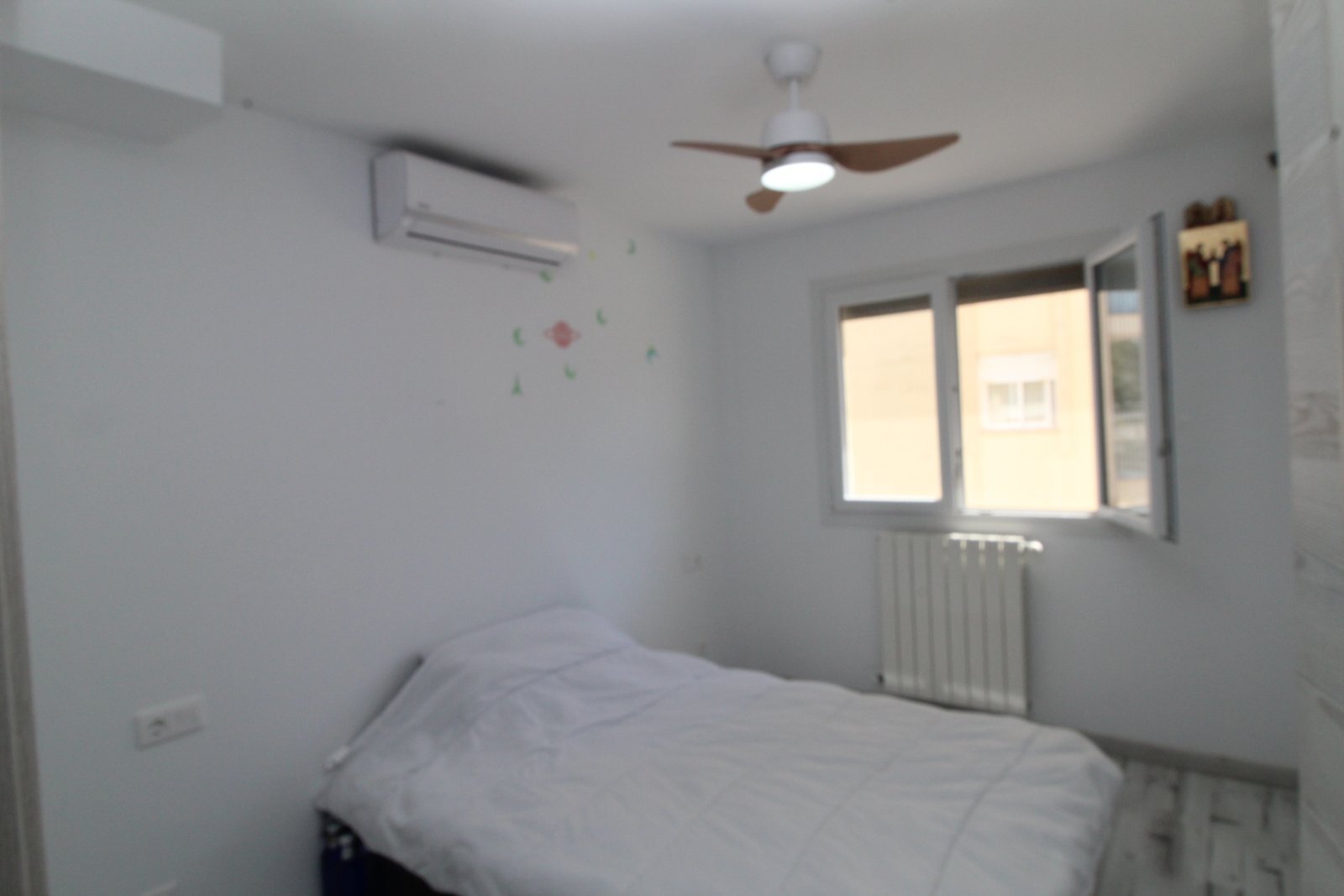 Helles Schlafzimmer mit Klimaanlage, Deckenventilator und Fensterfront zur Straße Helles Schlafzimmer mit Klimaanlage, Deckenventilator und Fensterfront zur Straße