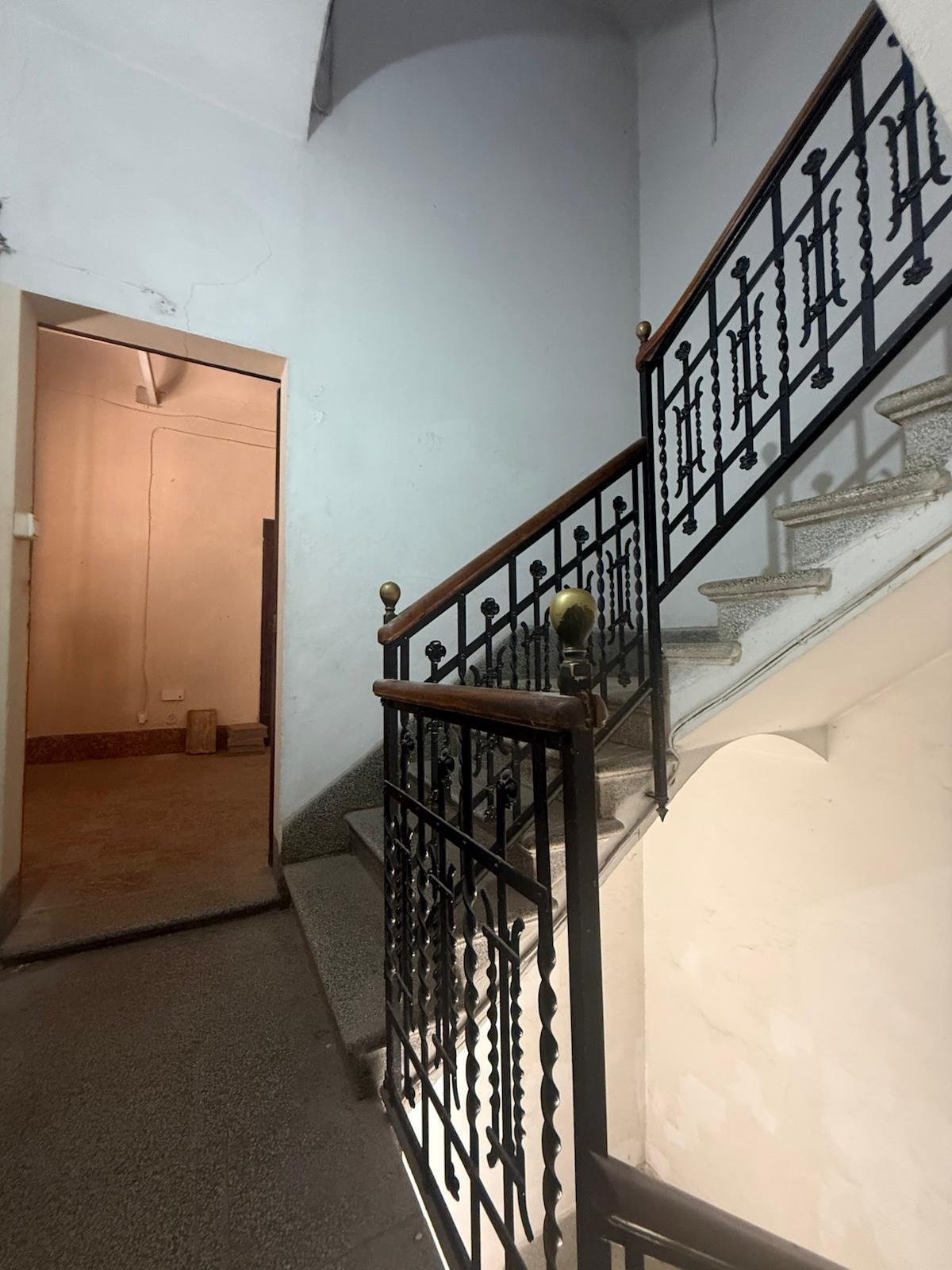 Elegante Treppenhausgestaltung mit dekorativem Metallgeländer und hohen Raumverhältnissen