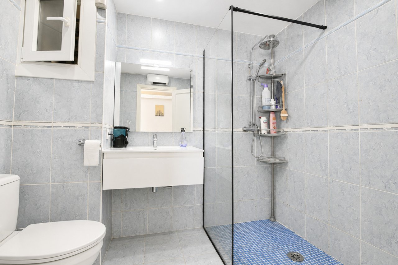 Modernes Badezimmer mit bodengleicher Dusche und praktischer Stauraum-Integration