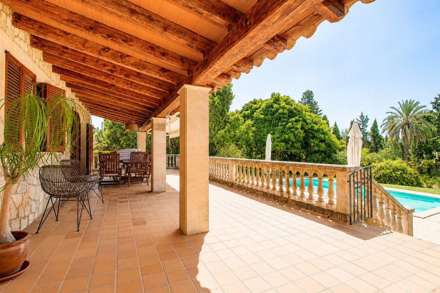 Überdachte Loggia mit massiven Holzbalken und direktem Poolzugang