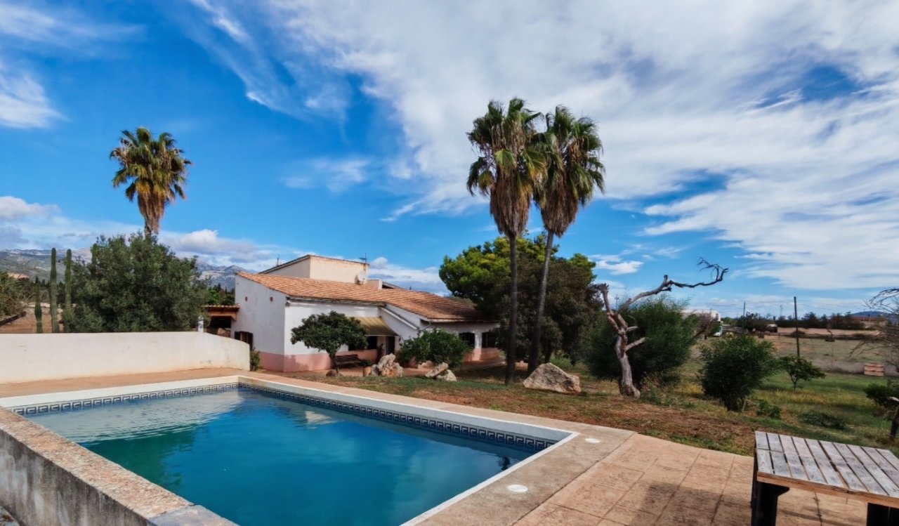 Swimmingpool mit sonniger Freiterrasse und Blick auf die weitläufige Landschaft