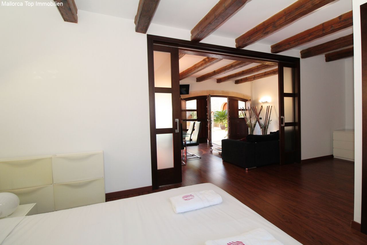 Schlafzimmer mit charaktervollen Holzbalken und eleganten Schiebetüren zum Wohnbereich Schlafzimmer mit charaktervollen Holzbalken und eleganten Schiebetüren zum Wohnbereich