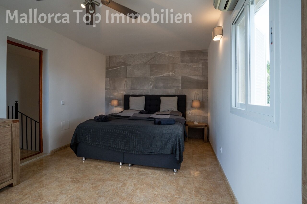 Hauptschlafzimmer mit eleganter Steinakzentwand und großflächigen Fensterfront Hauptschlafzimmer mit eleganter Steinakzentwand und großflächigen Fensterfront