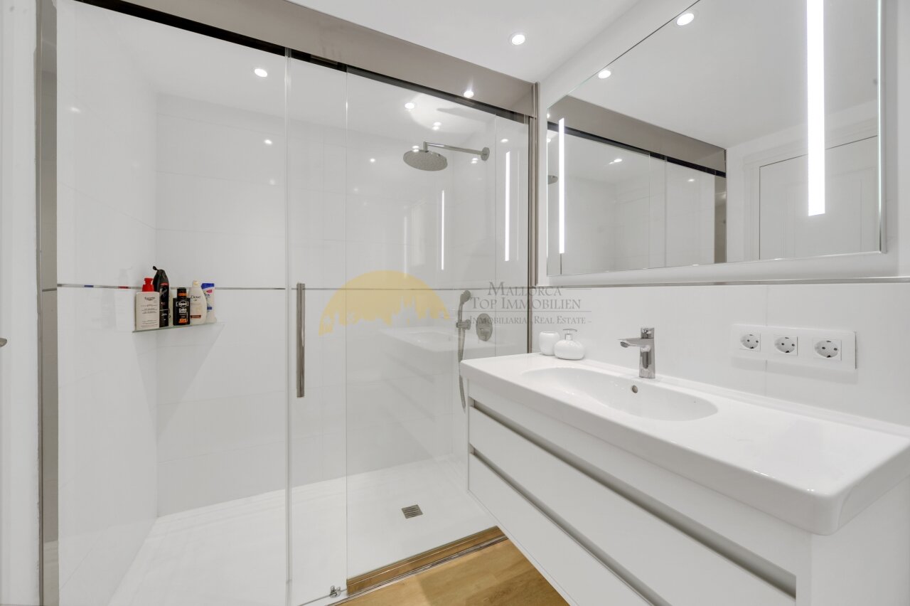 Modernes Badezimmer mit begehbarer Dusche, Doppelwaschbecken und hochwertiger Spiegelbeleuchtung