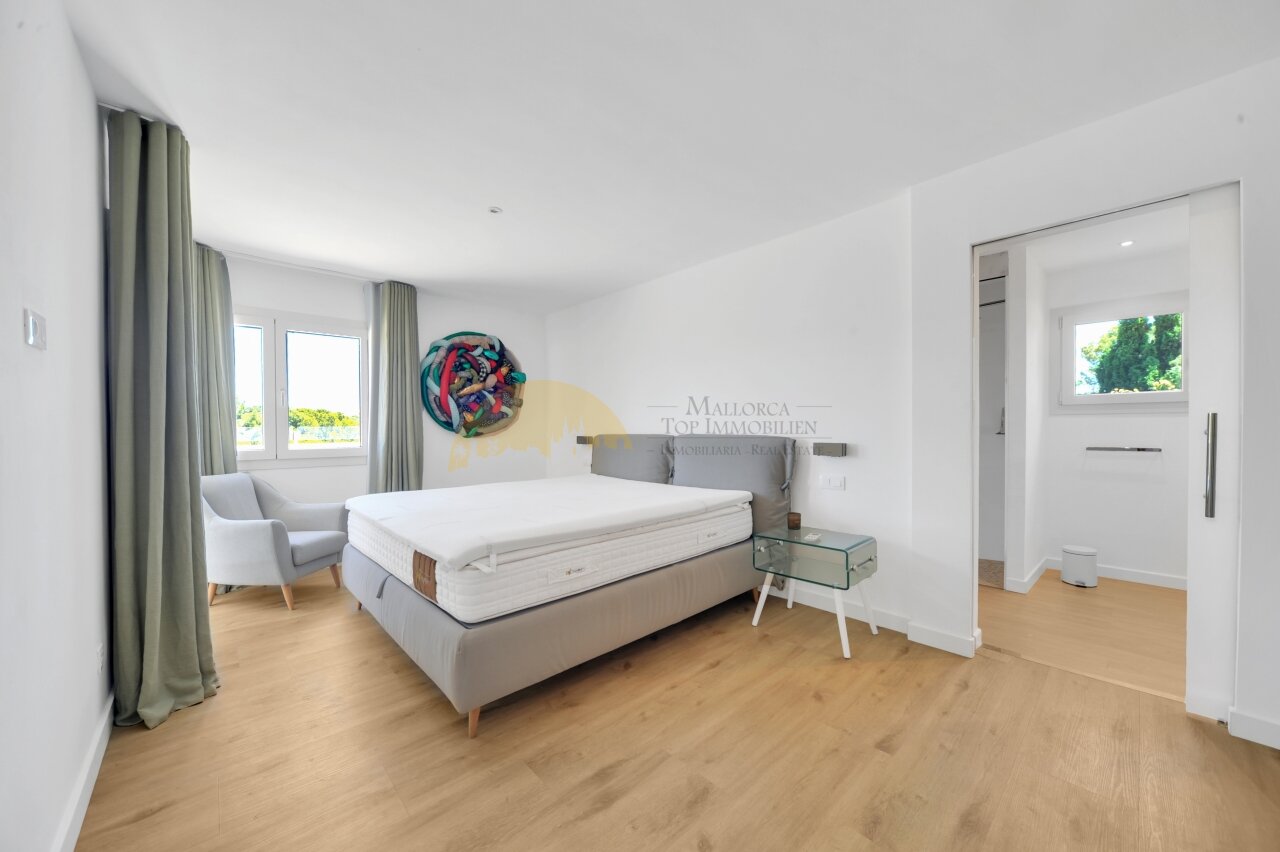 Helles Schlafzimmer mit großflächigen Fenstern, begehbarem Ankleidezimmer und direktem Terrassenzugang