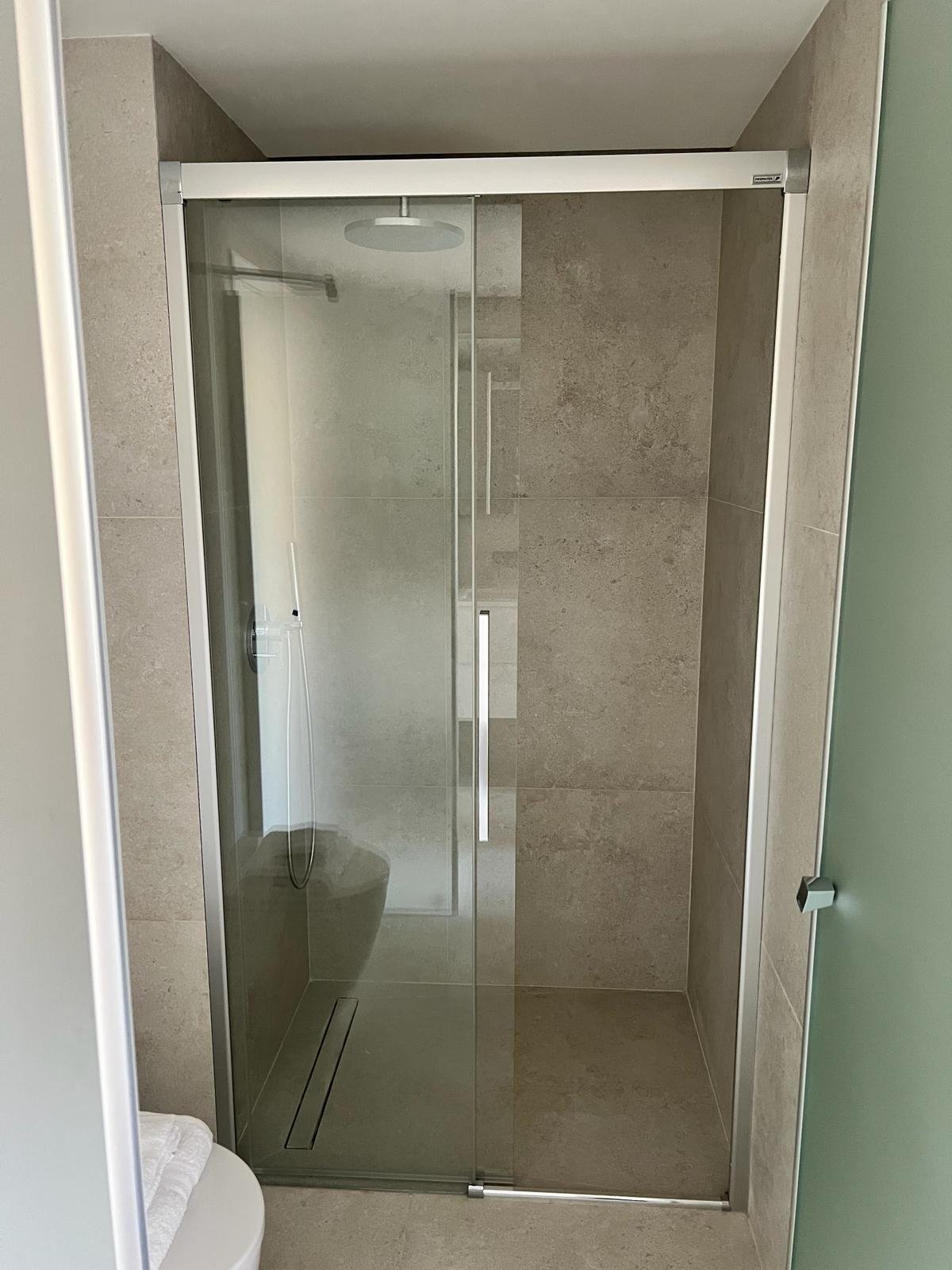 Ebenerdige Dusche mit rahmenloser Glasabtrennung und modernem Ablaufdesign Ebenerdige Dusche mit rahmenloser Glasabtrennung und modernem Ablaufdesign