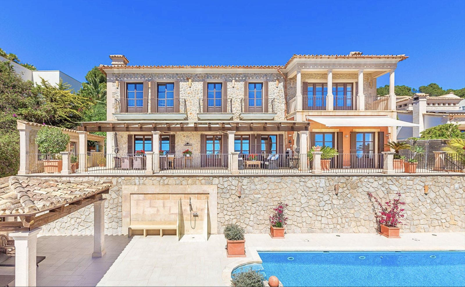 Mediterrane Fassade mit eleganten Loggien und hochwertiger Natursteinfassade – Architektur auf höchstem Niveau