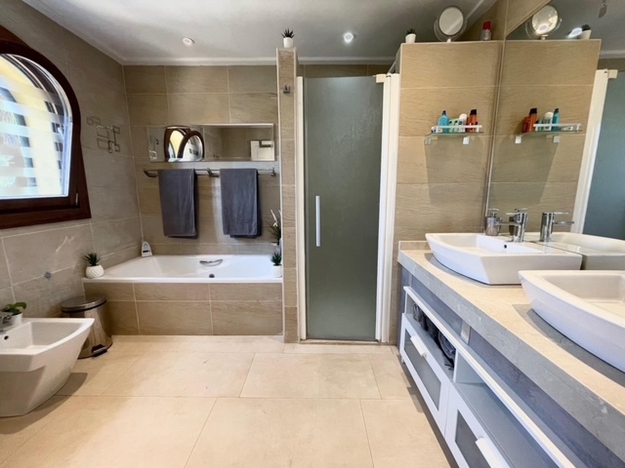Modernes Badezimmer mit zwei Waschtischen, begehbarer Dusche und umfangreichen Stauraummöglichkeiten