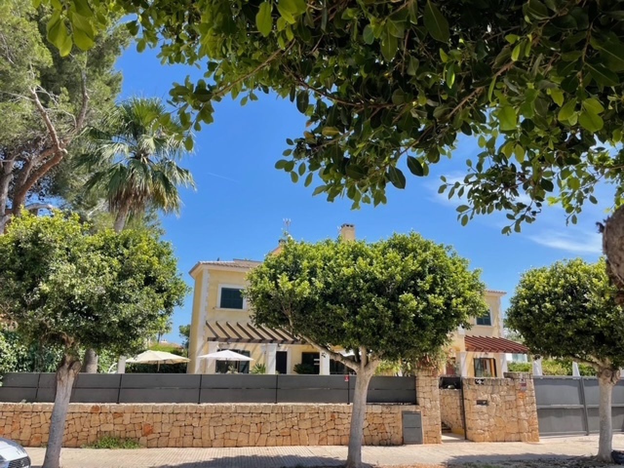 Mediterrane Fassade mit charaktervollem Steinmauerwerk und eleganter Toreinfahrt