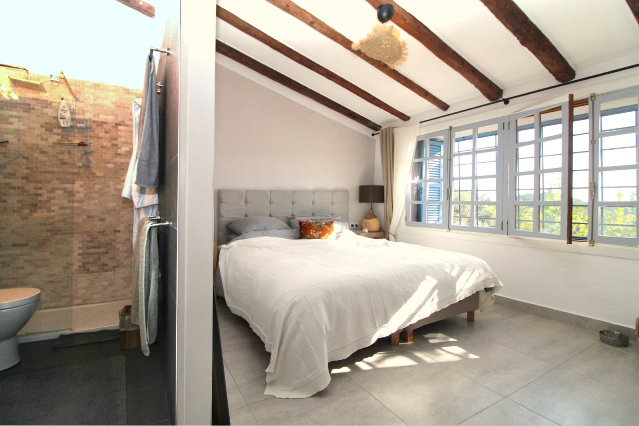 Hauptschlafzimmer mit Dachbalken-Charakter und großflächigen Fensterfront zum Naturblick
