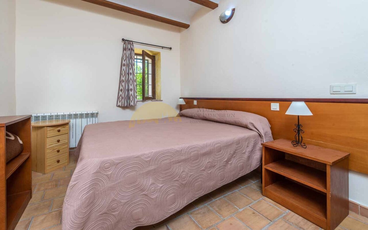 Schlafzimmer mit Holzbalkendecke und Fenster – Behagliche Raumausstattung mit Heizanlage und Natursteinboden