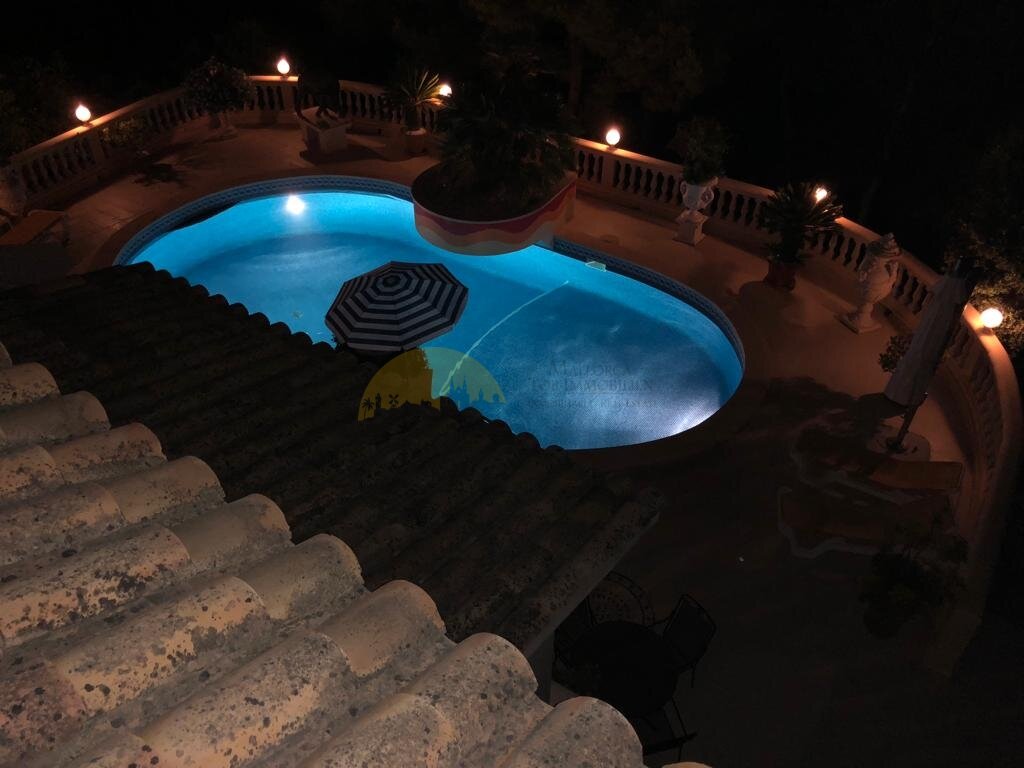 Poolanlage mit stimmungsvoller Nachtbeleuchtung und umlaufender Balkonterrasse