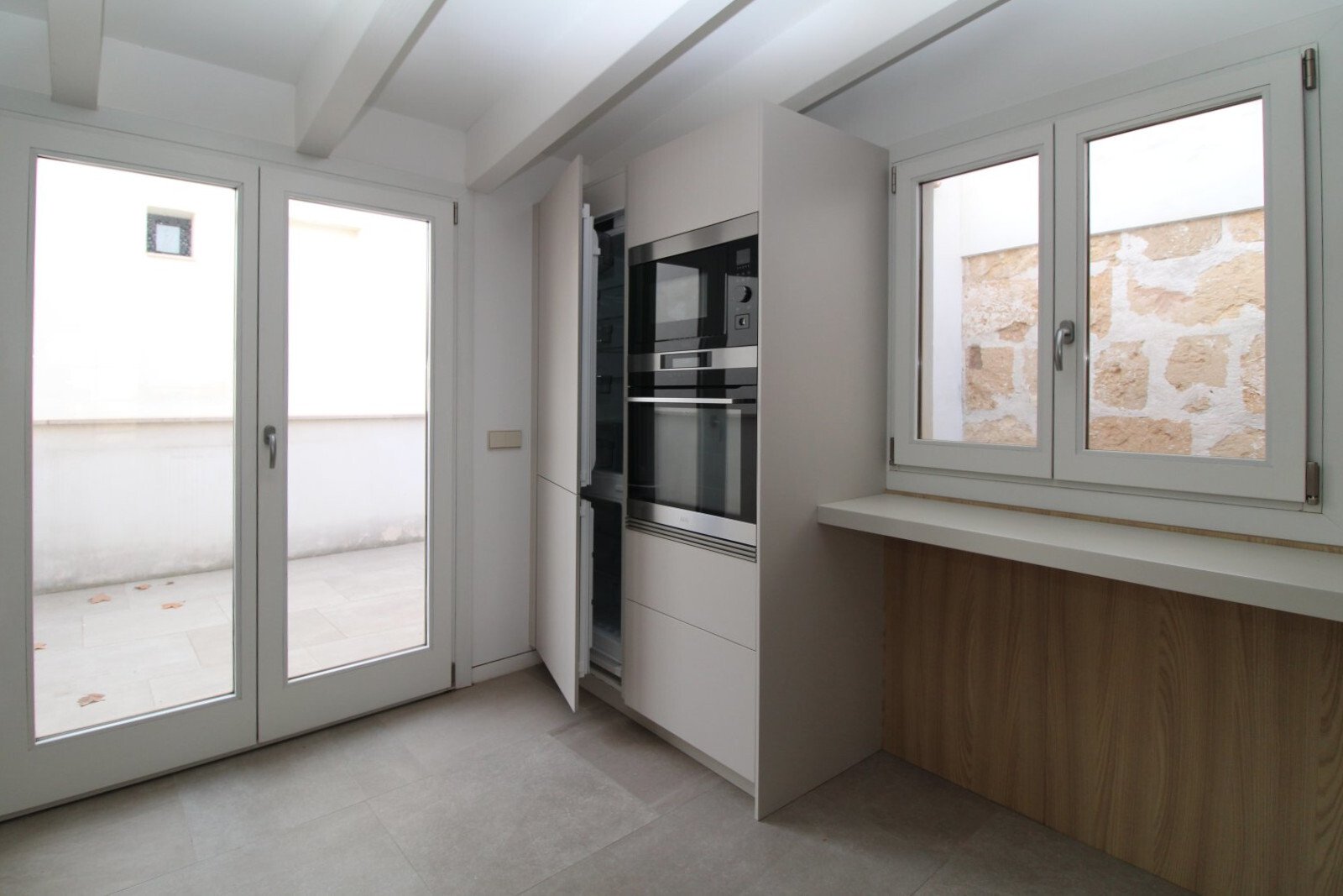 Moderne Küche mit hochwertigen Einbaugeräten und großflächigen Fenstern zum Außenbereich Moderne Küche mit hochwertigen Einbaugeräten und großflächigen Fenstern zum Außenbereich