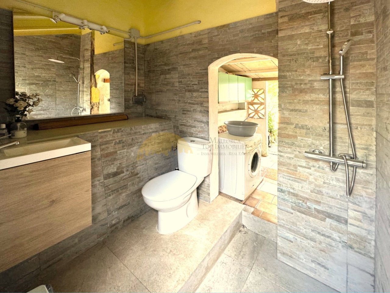 Modernes Badezimmer mit ebenerdiger Dusche, hochwertiger Natursteinverkleidung und praktischem Nebenraum Modernes Badezimmer mit ebenerdiger Dusche, hochwertiger Natursteinverkleidung und praktischem Nebenraum