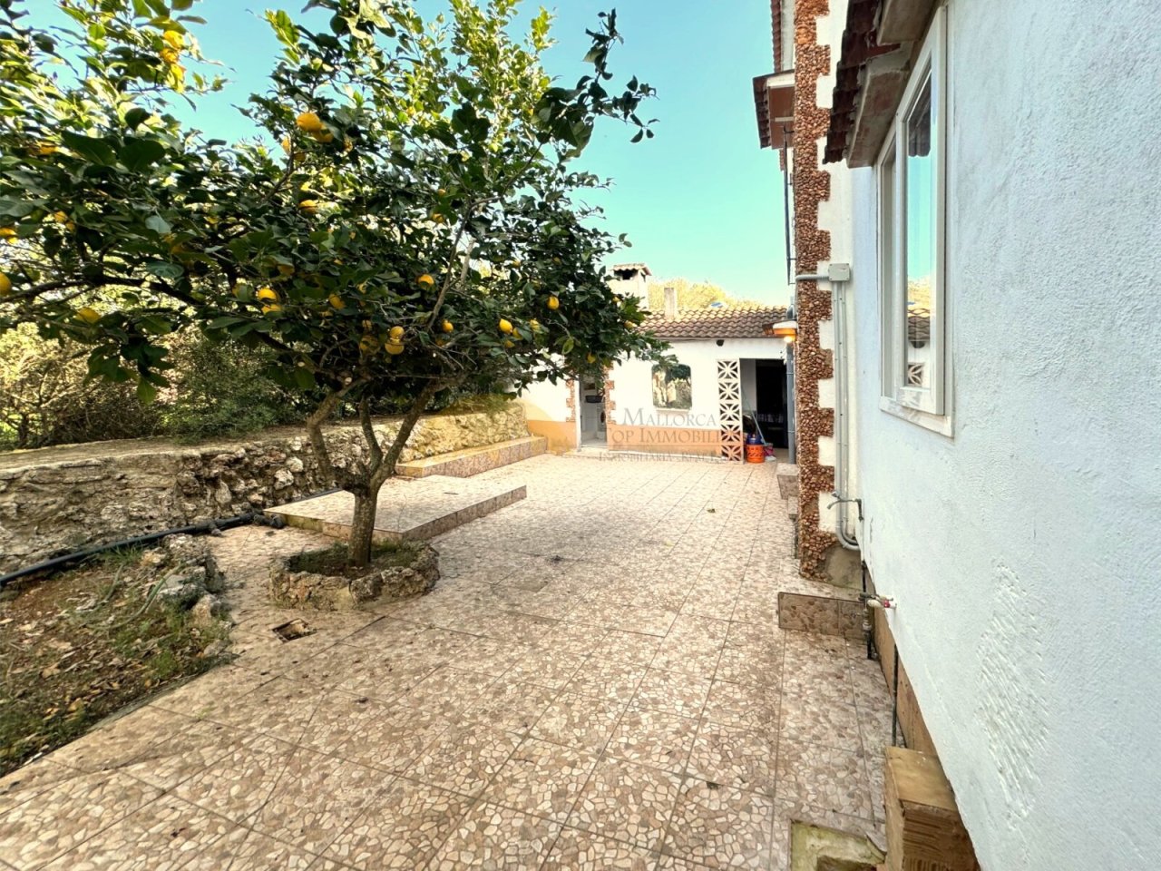 Terrassenbereich mit befestigter Fläche, Natursteinmauern und direktem Zugang zum Garten Terrassenbereich mit befestigter Fläche, Natursteinmauern und direktem Zugang zum Garten