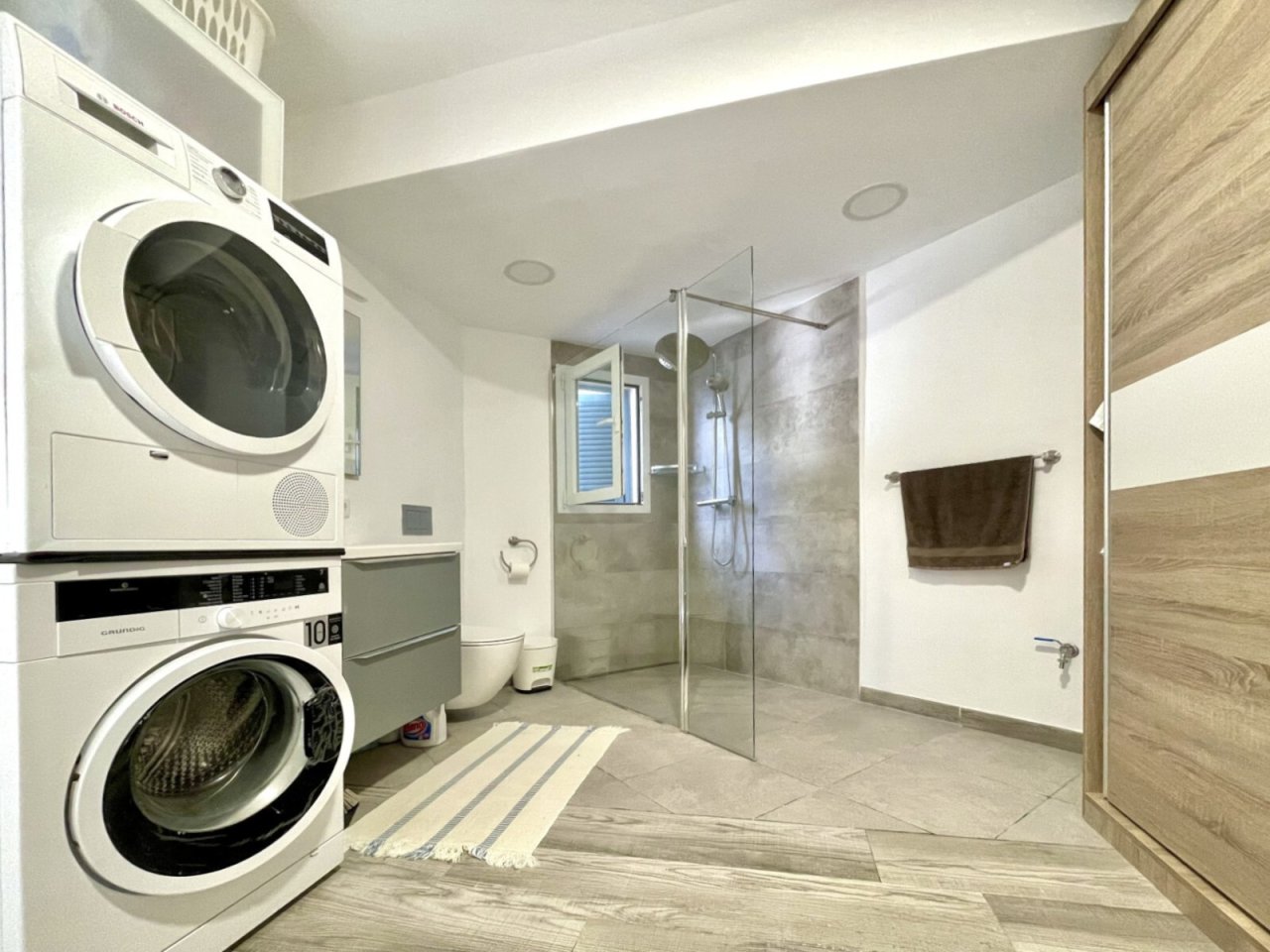 Luxurious washroom and bathroom with laundry area and walk-in shower with glass partition Luxurious washroom and bathroom with laundry area and walk-in shower with glass partition