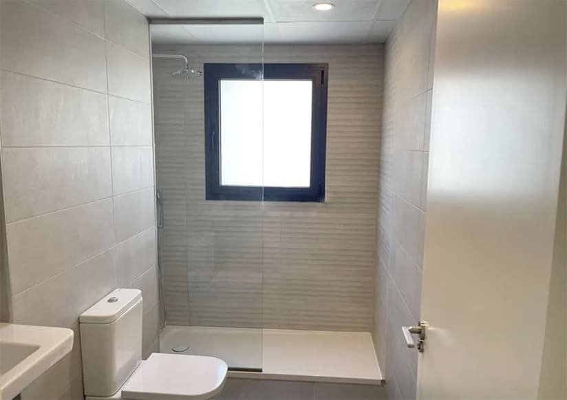 Modern bathroom with walk-in shower, glass partition, and window for natural lighting Modern bathroom with walk-in shower, glass partition, and window for natural lighting