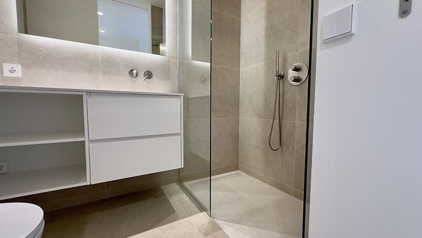 Modern bathroom with walk-in shower, washbasin unit, and LED mirror lighting Modern bathroom with walk-in shower, washbasin unit, and LED mirror lighting