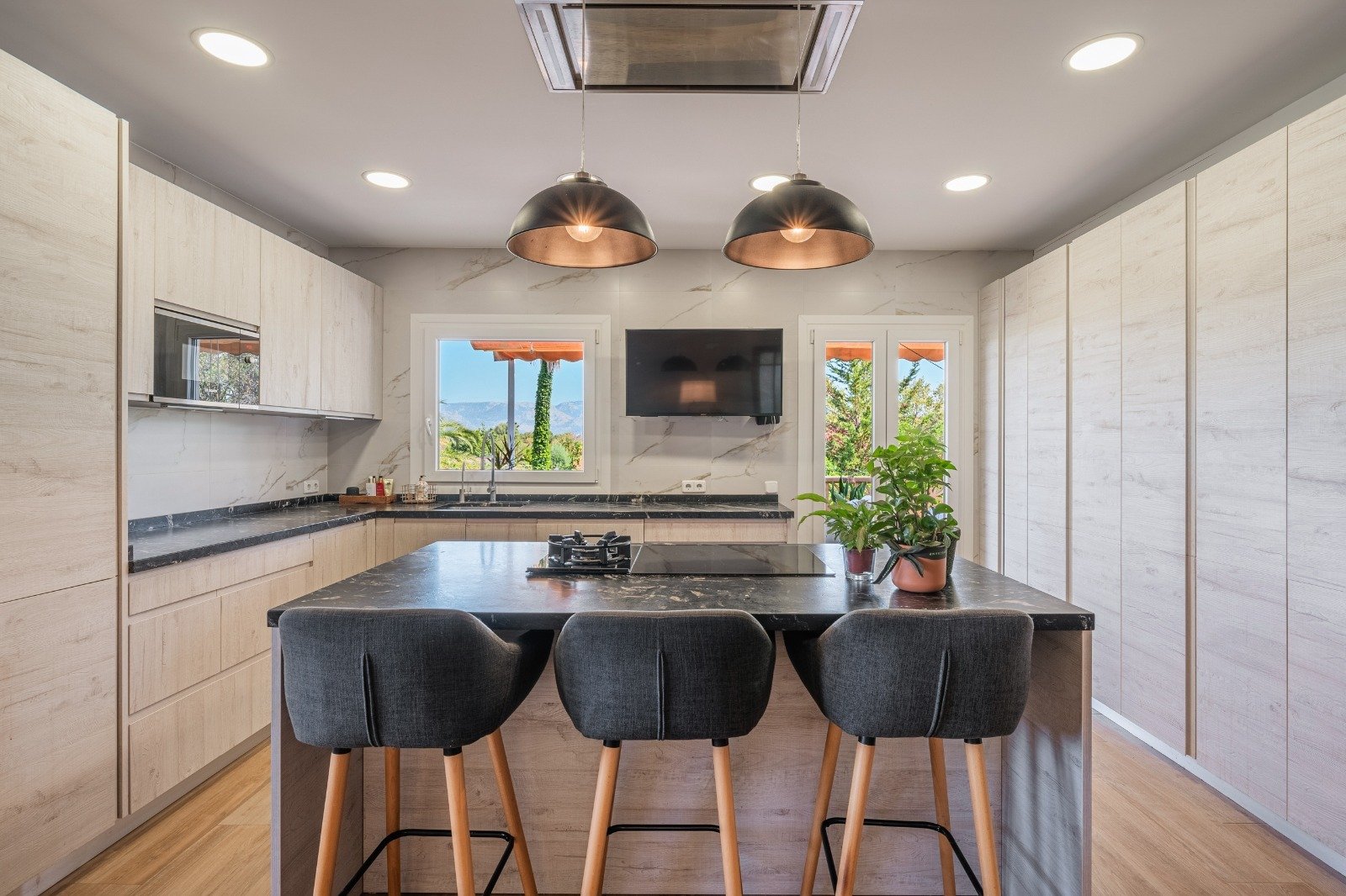Modern kitchen with a central island, high-quality built-in appliances, and large windows overlooking the garden