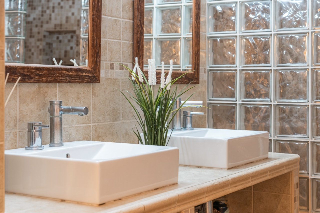 Elegant double vanity bathroom with frameless glass partition and natural flood of light