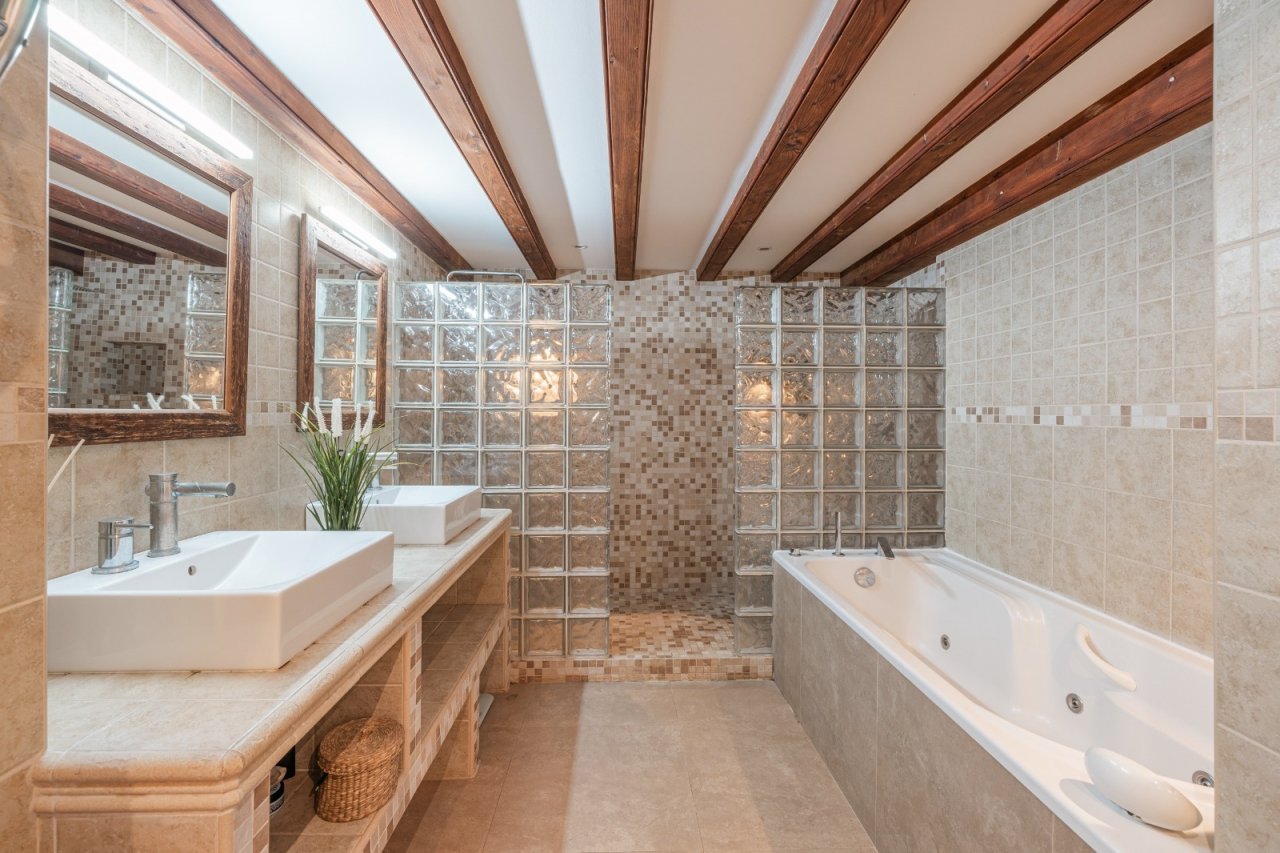 Luxurious bathroom with double vanity, freestanding bathtub, and walk-in shower under a wooden beam ceiling