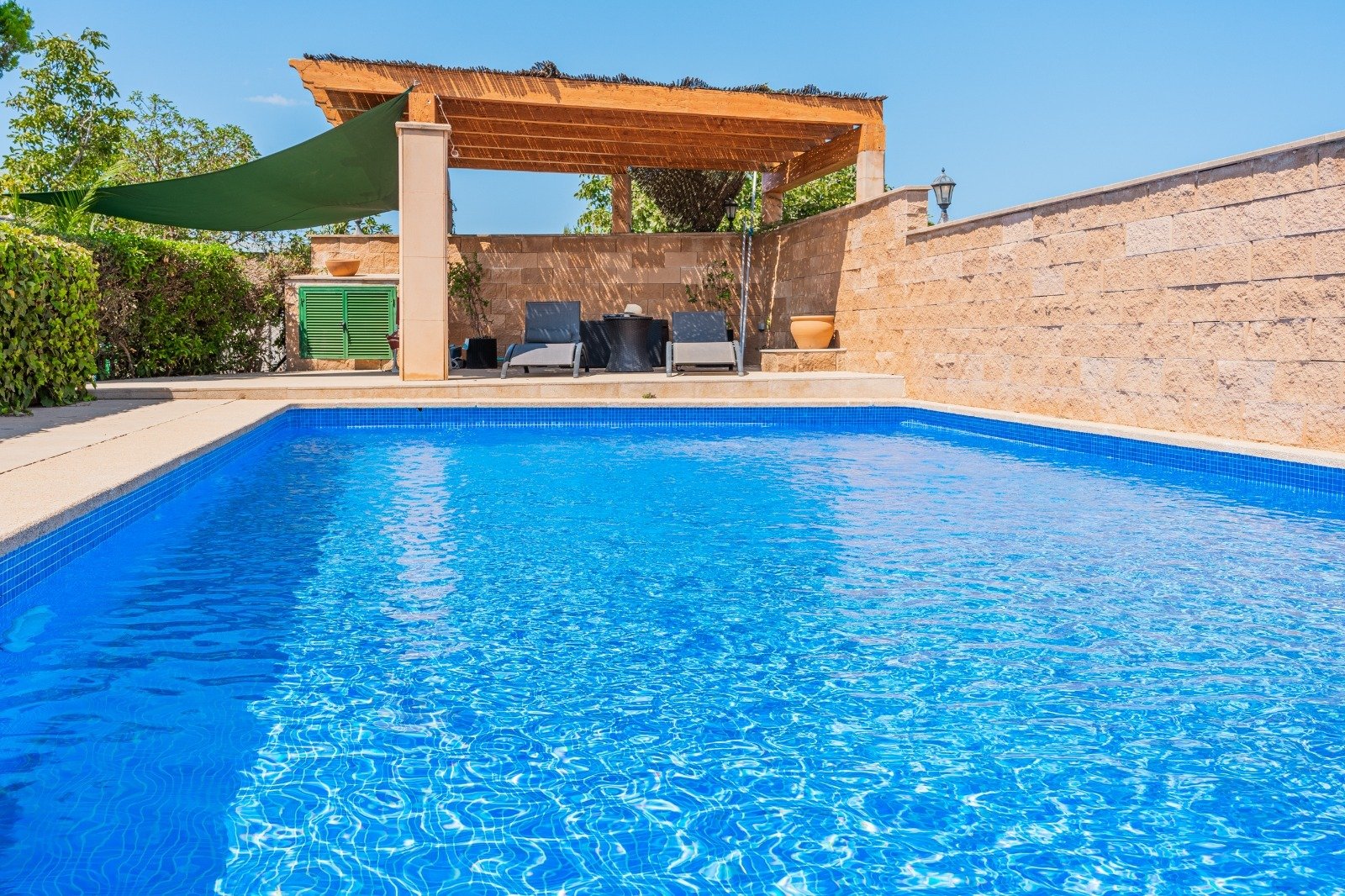 Refreshing pool area with a covered lounge and solid natural stone walls