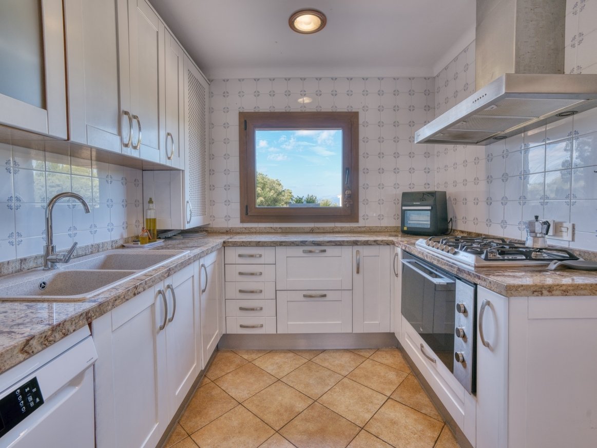 Functional kitchen with practical U-shape and window view of the greenery
