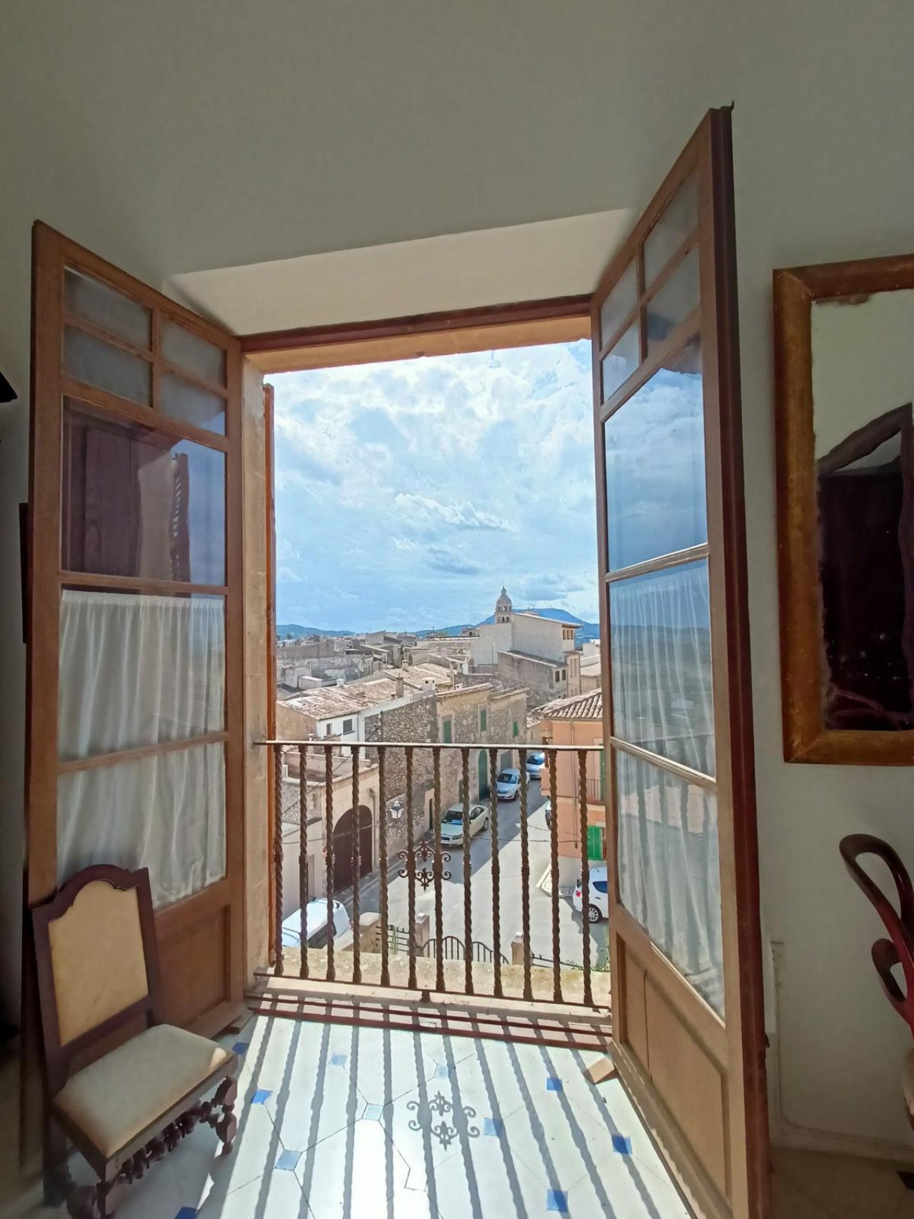 French doors with wrought iron balcony railing – view of the old town and mountain panorama