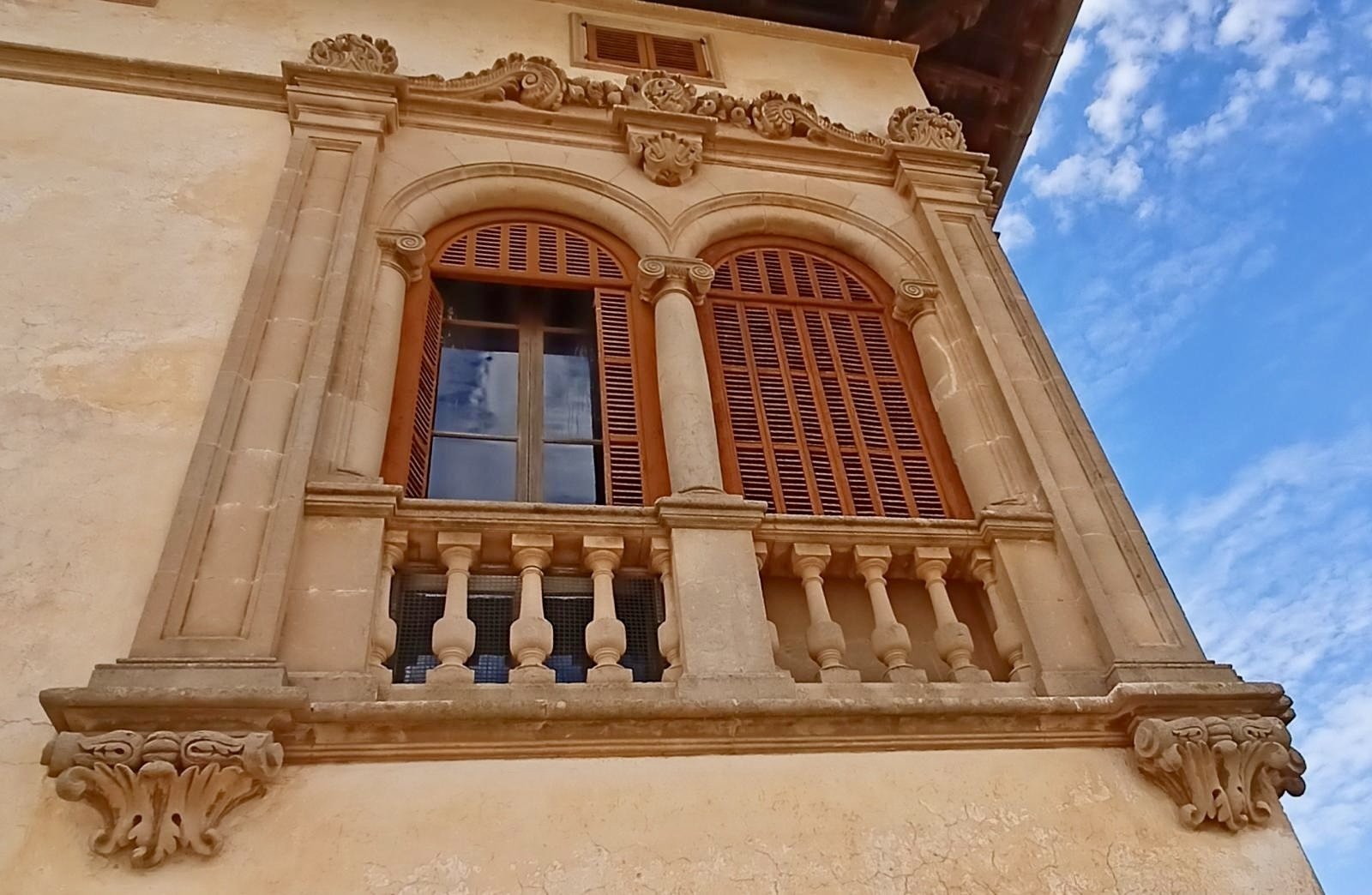 Classical-style window facade with elaborate ornamented stone framing and Juliet balcony
