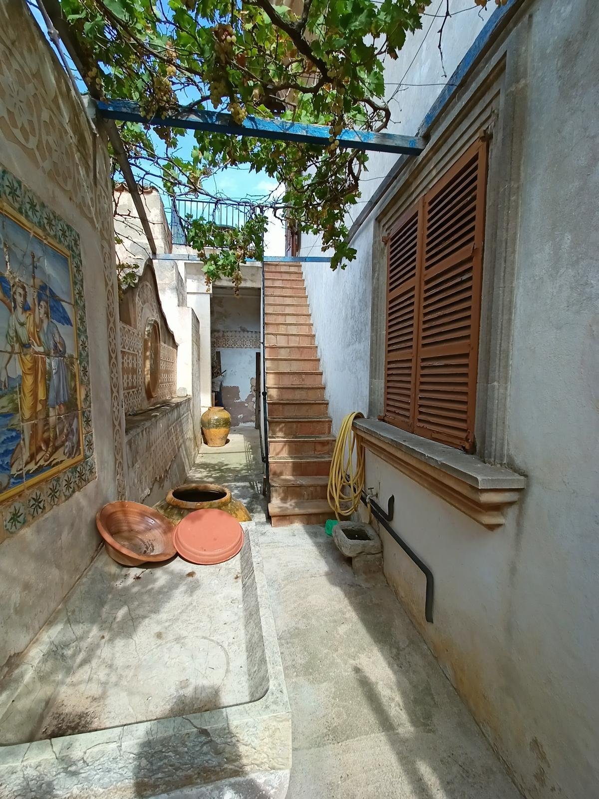 Charming courtyard entrance with authentic stone staircase and natural greenery – connection between the levels