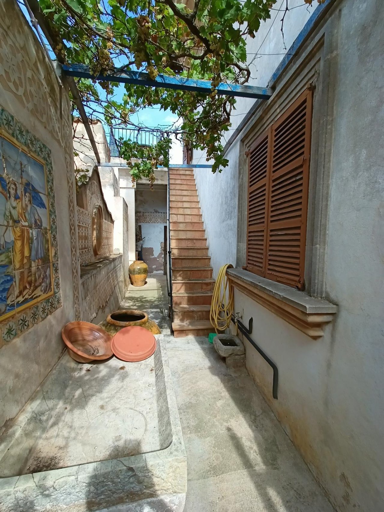 Charming courtyard entrance with authentic stone staircase and natural greenery – connection between the levels