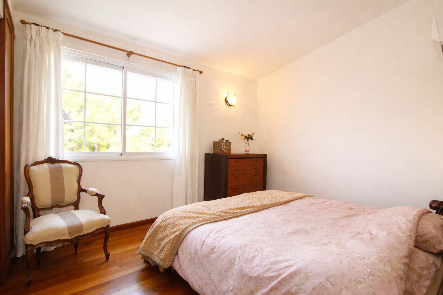 Bright bedroom with large window and parquet flooring