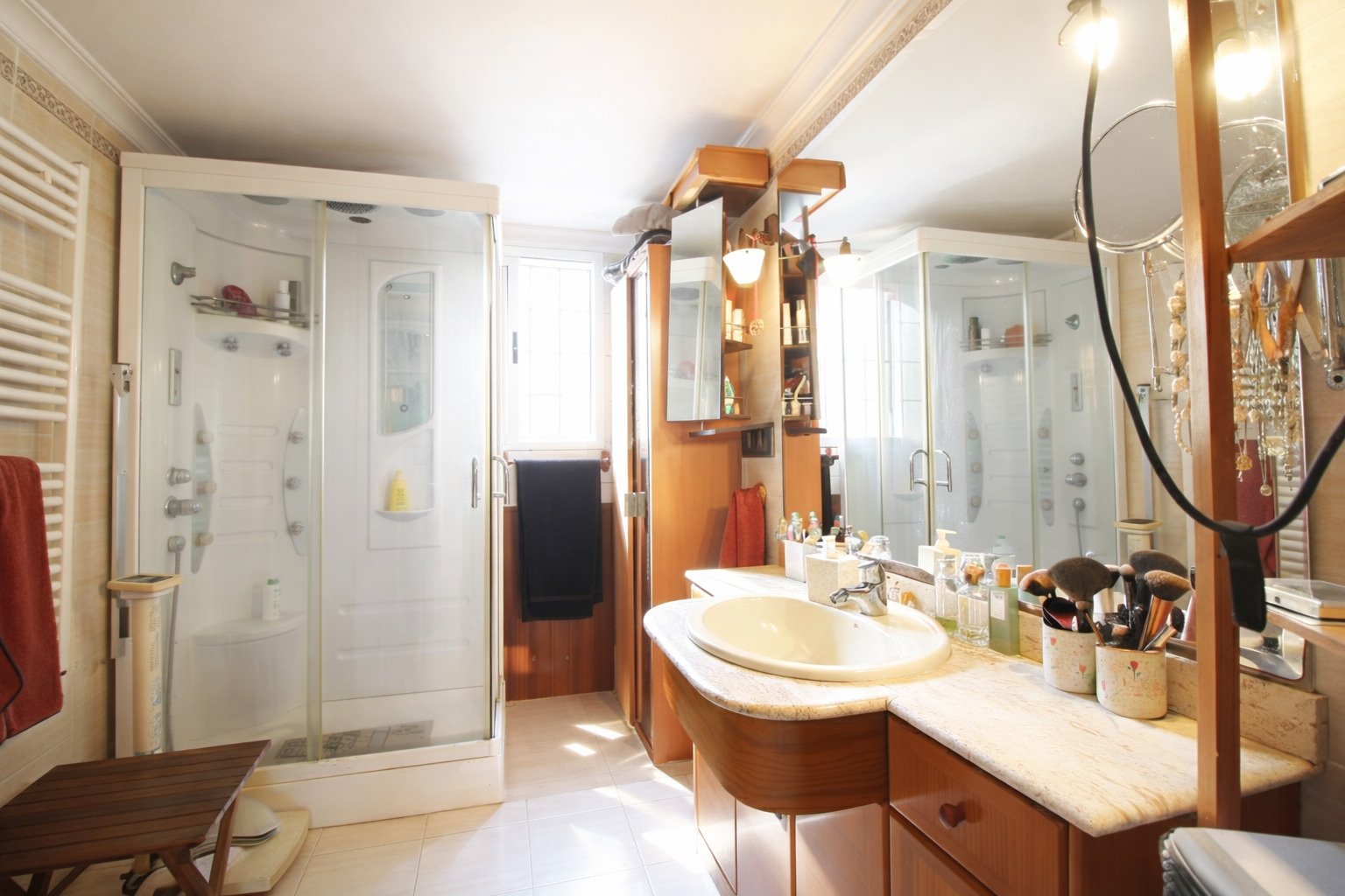 Luxurious bathroom with walk-in shower, double vanity, and integrated storage system