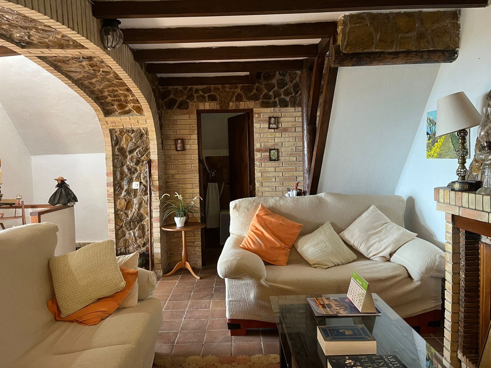 Living area with solid roof beams, natural stone arch, and authentic fireplace – a distinctive room atmosphere
